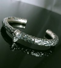 Twelve Small Skull On 7.5mm Chiseled Round Bar Bangle